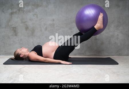 Portrait der hübschen Schwangeren trainiert mit Fitball im Fitnessstudio Stockfoto