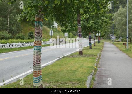 Die Hauptstraße in die Stadt ist mit Strick-/Häkelbäumen gesäumt. Das Strickkonzept hat eine breite Symbolik Stockfoto