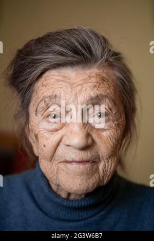 Ältere niedliche Frau von neunzig Jahre alt kaukasischen mit grauen Haaren und faltigen Gesicht sieht in der Kamera, nette Art Look und lächelt.Matur Stockfoto