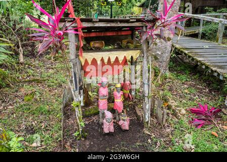 Familienfiguren in einem kleinen Ahnentempel in Sarawak auf Borneo Stockfoto