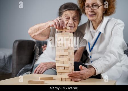 Reifer Arzt führt Sitzung, Therapie für ältere Patienten im Pflegeheim, Ausbildung feinmotorischen Fähigkeiten für Demenz, alzheimer Stockfoto