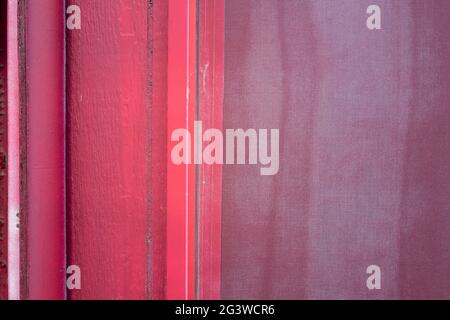 Detail eines Bildschirms auf dem Fenster eines rot gestrichenen Gebäudes Stockfoto