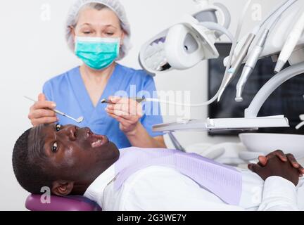 Zahnarzt ist die Behandlung von männlichen Patienten, die im zahnmedizinischen Stuhl sitzt. Stockfoto