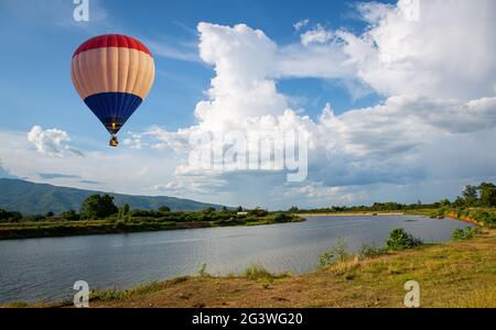 Heißluftballon, der über den Ping-Fluss fliegt, mit landschaftlichem Blick im Hintergrund in Chiang Mai Thailand. Stockfoto