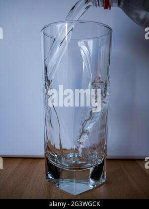 Wasser mit sichtbarem Flaschenhals in das Glas gießen - Bewegung des gefrorenen Wassers Stockfoto