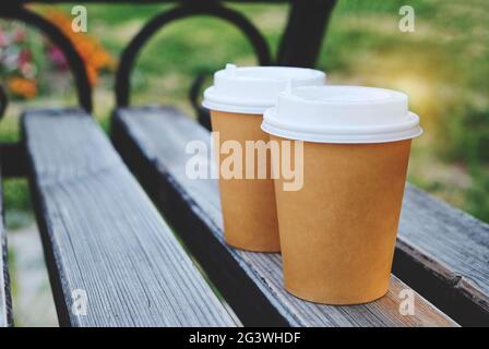 Zwei Tassen Kaffee zum Mitnehmen im Park auf einer Holzbank. Stockfoto
