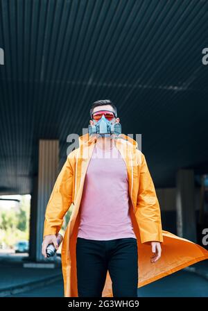Trendiger junger Mann mit Atemschutzmaske, der die Straße entlang läuft Stockfoto