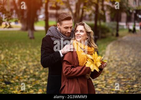 Liebevolles Paar in einem Herbstpark. Mann und Frau umarmten sich lächelnd und schauten sich im Herbstpark an. Außenaufnahme eines „You“ Stockfoto