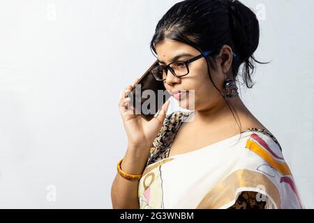 Eine schöne indische Frau im Saree spricht über Smartphone mit ernstem Gesicht isoliert auf weißem Hintergrund Stockfoto