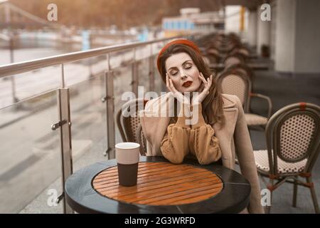 Pariser Frau mit Kaffeebecher auf der Straße der Stadt am Abend. Charmante Frau genießt ihre Tasse Kaffee in einem Frühling im Freien sitzen Stockfoto