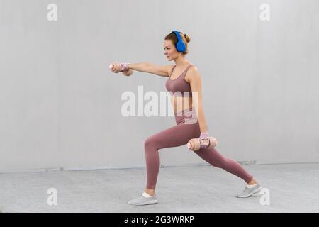 Schöne Fitness-Mädchen Training Beine und Gewichte heben. Mädchen in einem engen rosa Outfit mit Hanteln ausarbeiten. Mädchen macht spo Stockfoto