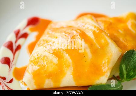 Nahaufnahme von Dessert-Pfannkuchen mit Erdbeermarmelade, Honig und einer weißen Kugel Eis. Stockfoto