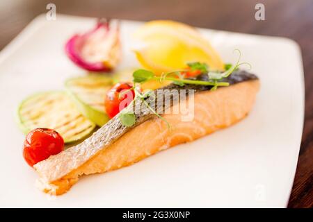 Platte mit Gemüse und Meeresfrüchten. Verschiedene Meeresfrüchte: Gebratene Calamari, gegrillte Garnelen mit Sauce. Gebackenes Fischfilet. Gewürze und Le Stockfoto