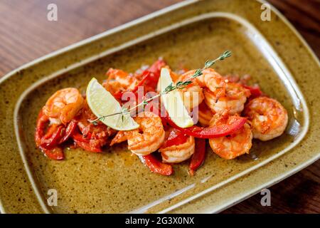 Platte mit Gemüse und Meeresfrüchten. Verschiedene Meeresfrüchte: Gebratene Calamari, gegrillte Garnelen mit Sauce. Gebackenes Fischfilet. Gewürze und Le Stockfoto