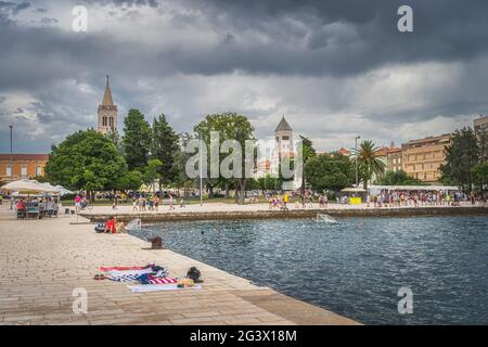 Massen von Touristen entspannen an der Küste in Zadar. Menschen spielen Wasserball in der Adria Stockfoto