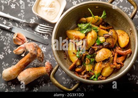 Gebratene Kartoffeln im Landhausstil mit Zwiebeln und geschmorten Pilzen und Kräutern. Servierbesteck: Besteck und Einrichtung. Konzept - Menü für ein Resta Stockfoto