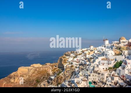 Windmühlen und Weiße Häuser an einem Berghang in Oia Town Stockfoto