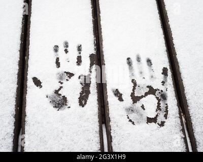 Abdrücke von Händen im Schnee auf einem Tisch im Freien Stockfoto