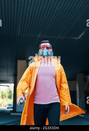 Trendiger junger Mann mit Atemschutzmaske, der die Straße entlang läuft Stockfoto