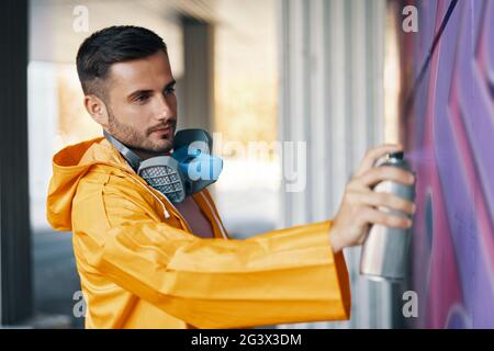 Straßenkünstler malt bunte Graffiti an die Wand Stockfoto