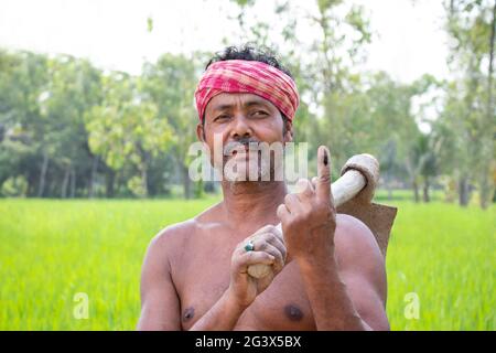 Porträt eines Bauern mit Schaufel und Wählermarkierung am Finger auf dem landwirtschaftlichen Feld Stockfoto