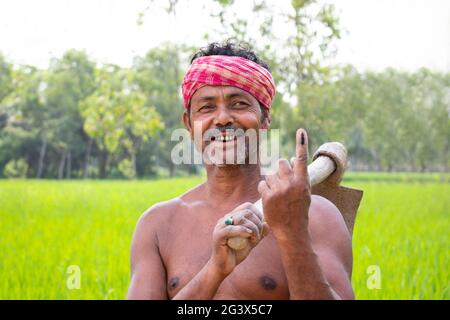 Porträt eines Bauern mit Schaufel und Wählermarkierung am Finger auf dem landwirtschaftlichen Feld Stockfoto