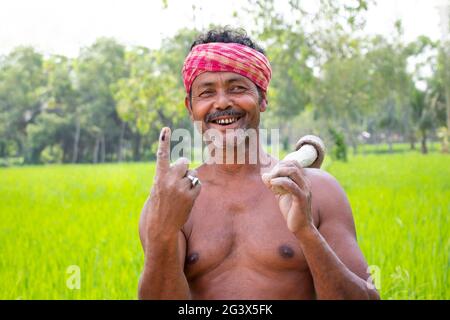 Porträt eines Bauern mit Schaufel und Wählermarkierung am Finger auf dem landwirtschaftlichen Feld Stockfoto