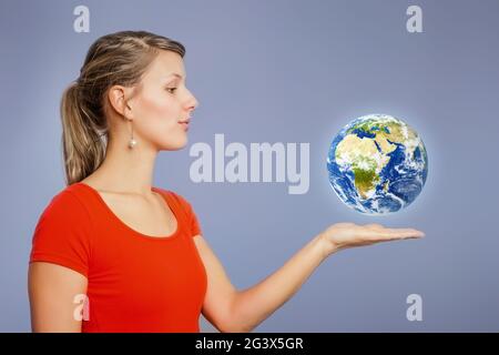 Frau, die den Planeten Erde über ihrer Hand beobachtet Stockfoto