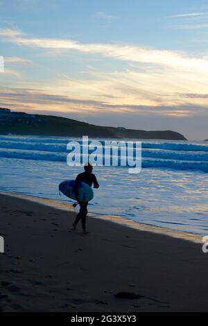 Surfer bei Sonnenuntergang am Fistral Beach, Newquay, Cornwall, Großbritannien Stockfoto