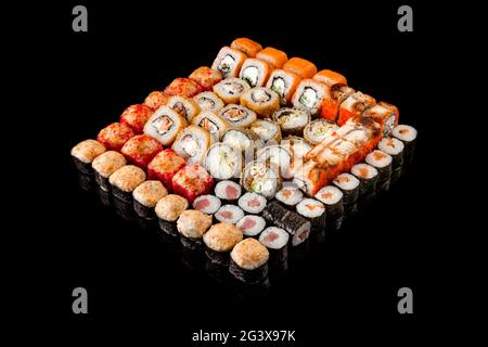 Großer Satz japanischer Rollen auf schwarzem Hintergrund. Lachs, Thunfisch, geräucherter Aal. Nahaufnahme, Draufsicht. Konzept für die Lieferung von Lebensmitteln. Stockfoto