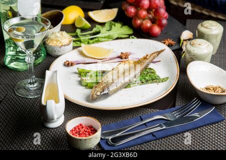 Ganze Kadaver der Meerforelle auf dem Grill. Gebratener roter Fisch mit Gemüse und Sauce. Nahaufnahme. Konzept - Essen, Delikatessen. Stockfoto