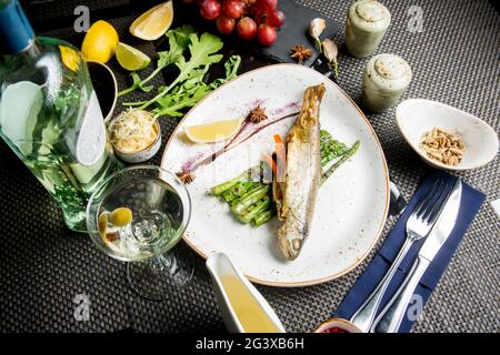 Ganze Kadaver der Meerforelle auf dem Grill. Gebratener roter Fisch mit Gemüse und Sauce. Nahaufnahme. Konzept - Essen, Delikatessen. Stockfoto