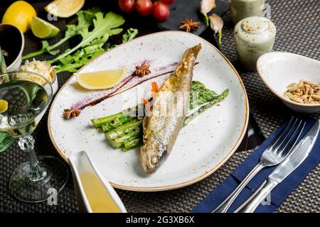 Ganze Kadaver der Meerforelle auf dem Grill. Gebratener roter Fisch mit Gemüse und Sauce. Nahaufnahme. Konzept - Essen, Delikatessen. Stockfoto