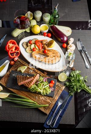 Gegrilltes Flusslachssteak. Gebratener roter Fisch mit Gemüse und Sauce. Nahaufnahme. Konzept - Essen, Delikatessen. Stockfoto