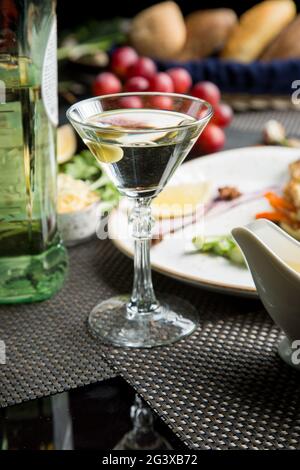 Ein Glas halbtrockener Weißwein, ein Aperitif. Wein mit gegrilltem Fleisch und Gemüse. Nahaufnahme. Konzept - Tabelleneinstellung in einem Restaurant Stockfoto