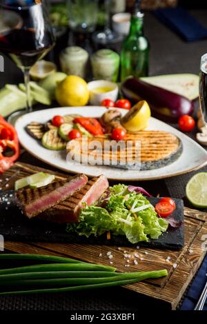 Gegrilltes Flusslachssteak. Gebratener roter Fisch mit Gemüse und Sauce. Nahaufnahme. Konzept - Essen, Delikatessen. Stockfoto