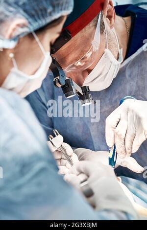 Chirurgen Männer und Frauen in einem Team während einer Operation über dem Operationstisch führen Ärzte in modernen Geräten eine onkologische Operation durch. Stockfoto