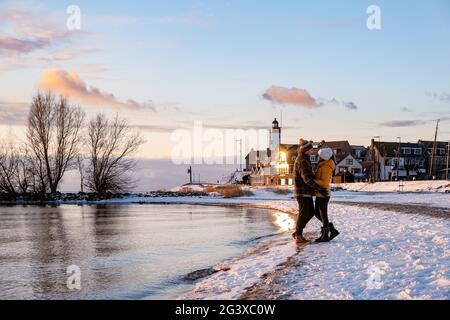 Paar Männer und Frauen am Leuchtturm von Urk Niederlande im Winter im Schnee Stockfoto