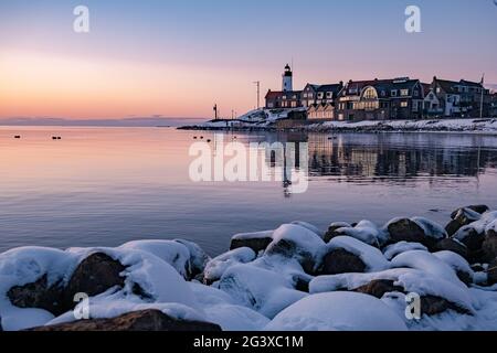 Winter in Urk mit Deich und Strand am Leuchtturm von Urk im Winter schneebedeckt, Sonnenuntergang am Leuchtturm von Urk Flevo Stockfoto