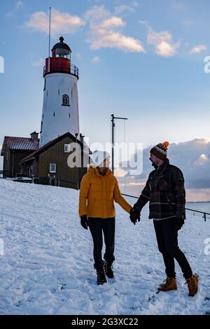 Paar Männer und Frauen am Leuchtturm von Urk Niederlande im Winter im Schnee Stockfoto