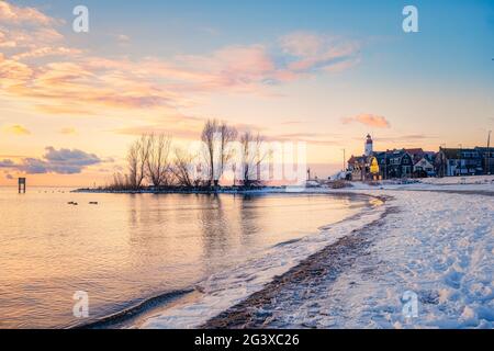 Winter in Urk mit Deich und Strand am Leuchtturm von Urk im Winter schneebedeckt, Sonnenuntergang am Leuchtturm von Urk Flevo Stockfoto