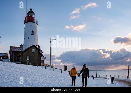 Paar Männer und Frauen am Leuchtturm von Urk Niederlande im Winter im Schnee Stockfoto