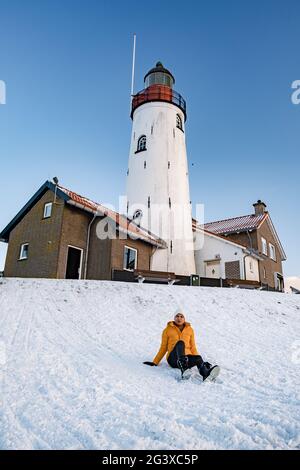 Frau am Leuchtturm von Urk Niederlande im Winter im Schnee Stockfoto