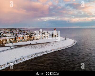 Schneebedeckter Strand während der Wnter durch Urk Leuchtturm in den Niederlanden Stockfoto