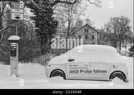 Winter in der Stadt â € "Elektroauto auf dem Parkplatz und schneebedeckt. Stockfoto