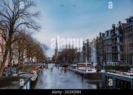 Eislaufen auf den Kanälen in Amsterdam, Niederlande im Winter, gefrorene Kanäle in Amsterdam im Winter Stockfoto