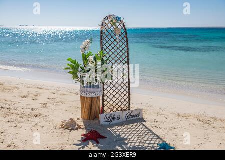 Nahaufnahme von Hochzeitszeichen und Dekorationen auf tropischen Insel sandig Strandparadies mit Meer im Hintergrund Stockfoto