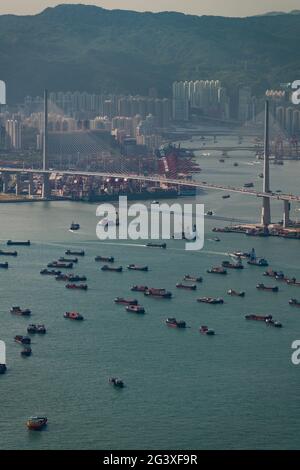 Lastkähne und Feuerzeuge, die für den Transfer von Schiffscontainern zu und von Schiffen verwendet werden, die außerhalb des Containerhafens von Hongkong, Victoria Harbour, festgemacht wurden Stockfoto