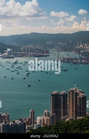 Lastkähne und Feuerzeuge, die für den Transfer von Schiffscontainern zu und von Schiffen verwendet werden, die außerhalb des Containerhafens von Hongkong, Victoria Harbour, festgemacht wurden Stockfoto