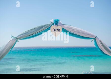 Setup von Hochzeit ehe Gang mit Vorhängen und Bogen auf Sandy Tropical Beach Paradise Ocean Hintergrund zu öffnen. Stockfoto